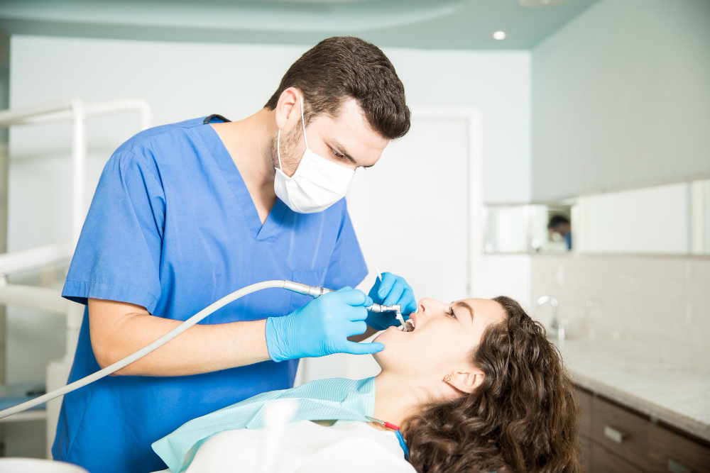 Young woman receiving dental treatment from male dentist in dental clinic